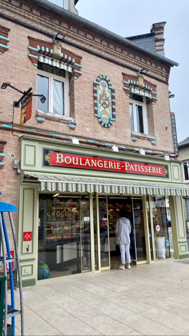 Tageslichtbild einer Bäckerei mit rotem Schild und dekorativem Portal.
