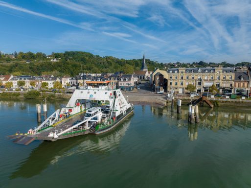 Fähre im Wasser vor einer malerischen Stadt mit historischen Gebäuden.