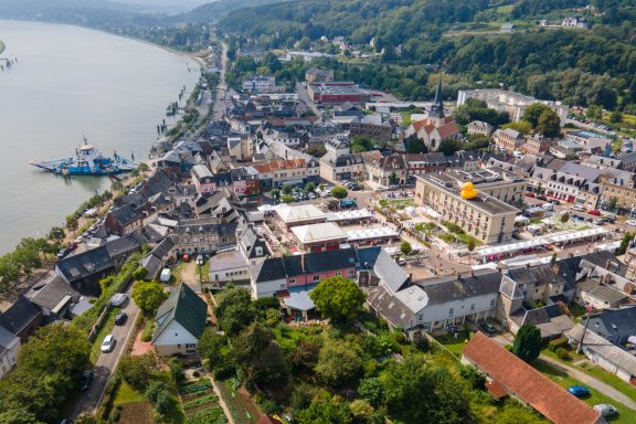 Luftaufnahme eines kleinen Stadtgebiets am Fluss mit Häusern und Vegetation.